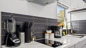 A modern kitchen with a black and white backsplash, a built-in stove, and a window with a view of the outdoors. - Cityscapes Studio Suite #D @ East Downtown (Houston)