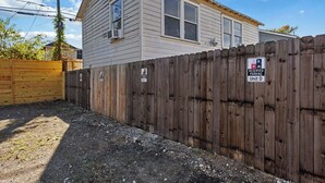 A two-story house with a wooden fence, a reserved parking sign, and a clear sky. - Cityscapes Studio Suite #D @ East Downtown (Houston)