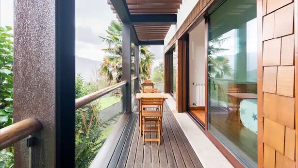 A balcony with wooden furniture and a glass door leading to a room. - Wonderful 5-bedroom villa in Rio Caldo perfect for your getaway (Rio caldo)