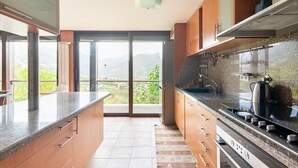 A modern kitchen with a large island, built-in oven, and a view of a mountainous landscape through large sliding doors. - Wonderful 5-bedroom villa in Rio Caldo perfect for your getaway (Rio caldo)
