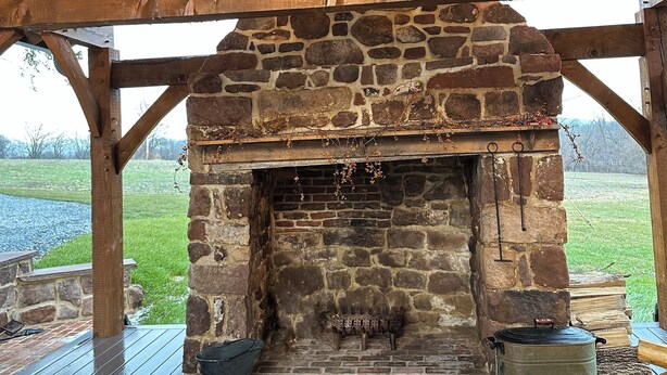 Una chimenea de piedra bajo un techo de madera con un farol colgante.