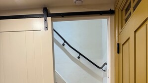 Una escalera de madera con barandilla negra que lleva a un rellano.