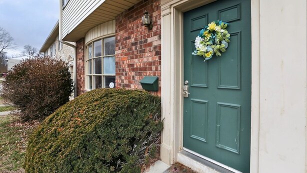 A house with a green door, a brick exterior, and a small window.