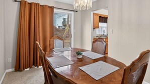 A dining area with a wooden table, four chairs, and a chandelier.