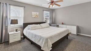 A bedroom with a bed, nightstand, dresser, and ceiling fan.