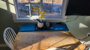 Ein Holztisch mit einem blauen Kissen, einem weißen Stuhl und einer Vase mit gelben Blumen.