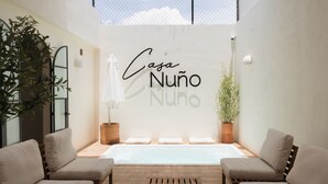 A spa area with a pool, two sofas, a wooden table, and a sign reading "Casa Nuño". - Oasis with Swimming Pool in the Heart of Oaxaca (Oax.)