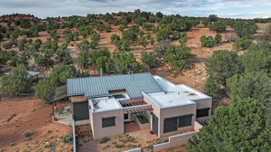 Una casa moderna amb teulada plana, grans finestres i zona de pati.