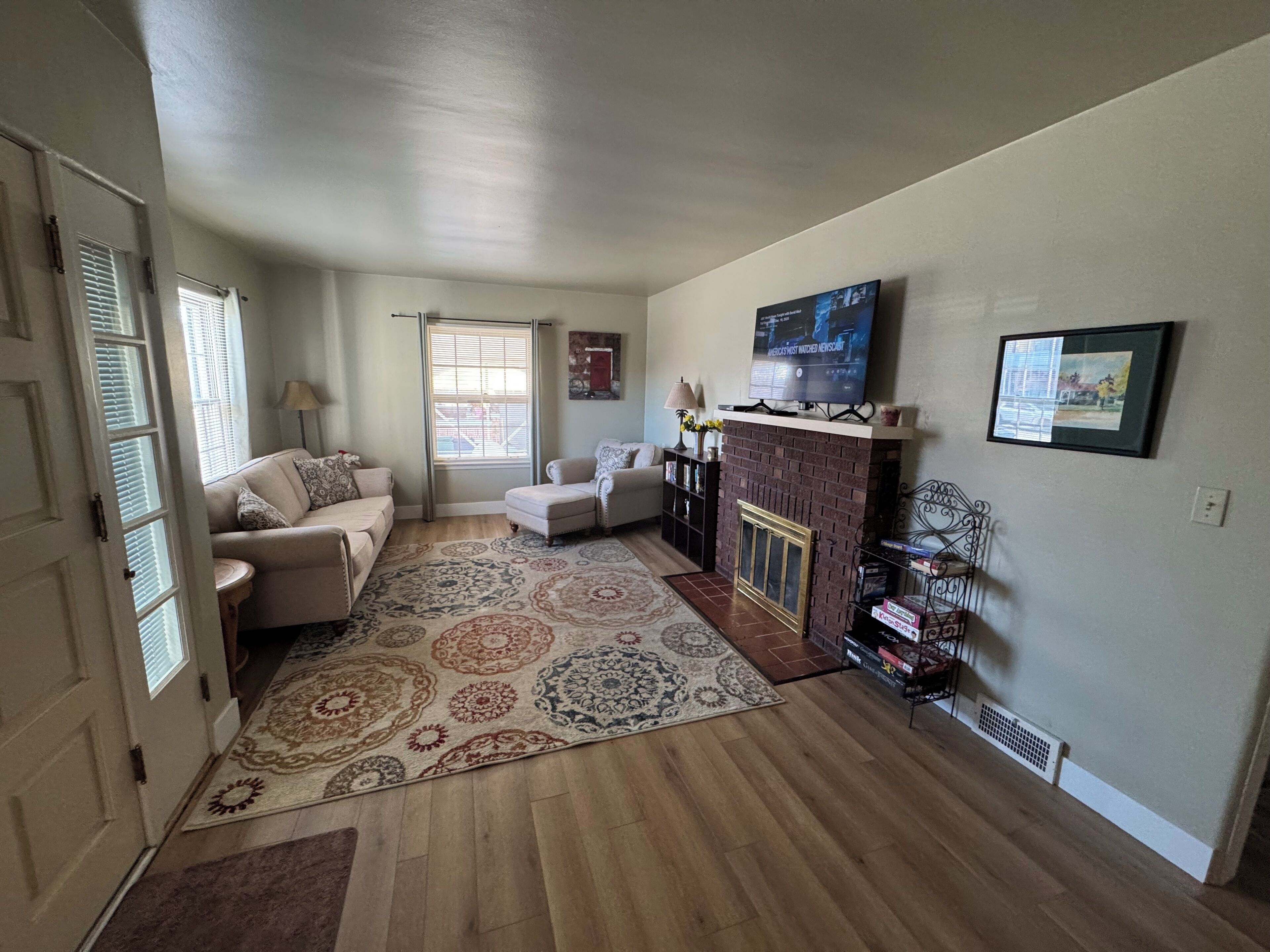 A living room with a fireplace, a television mounted above it, and a large rug on the floor.
