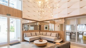A modern hotel lobby with a large L-shaped sectional sofa, a round coffee table, and a grey armchair. - Modern Apartment in Cambuí (Campinas)