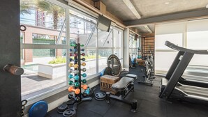 A gym with a weight rack, dumbbells, a bench, and a treadmill. - Modern Apartment in Cambuí (Campinas)