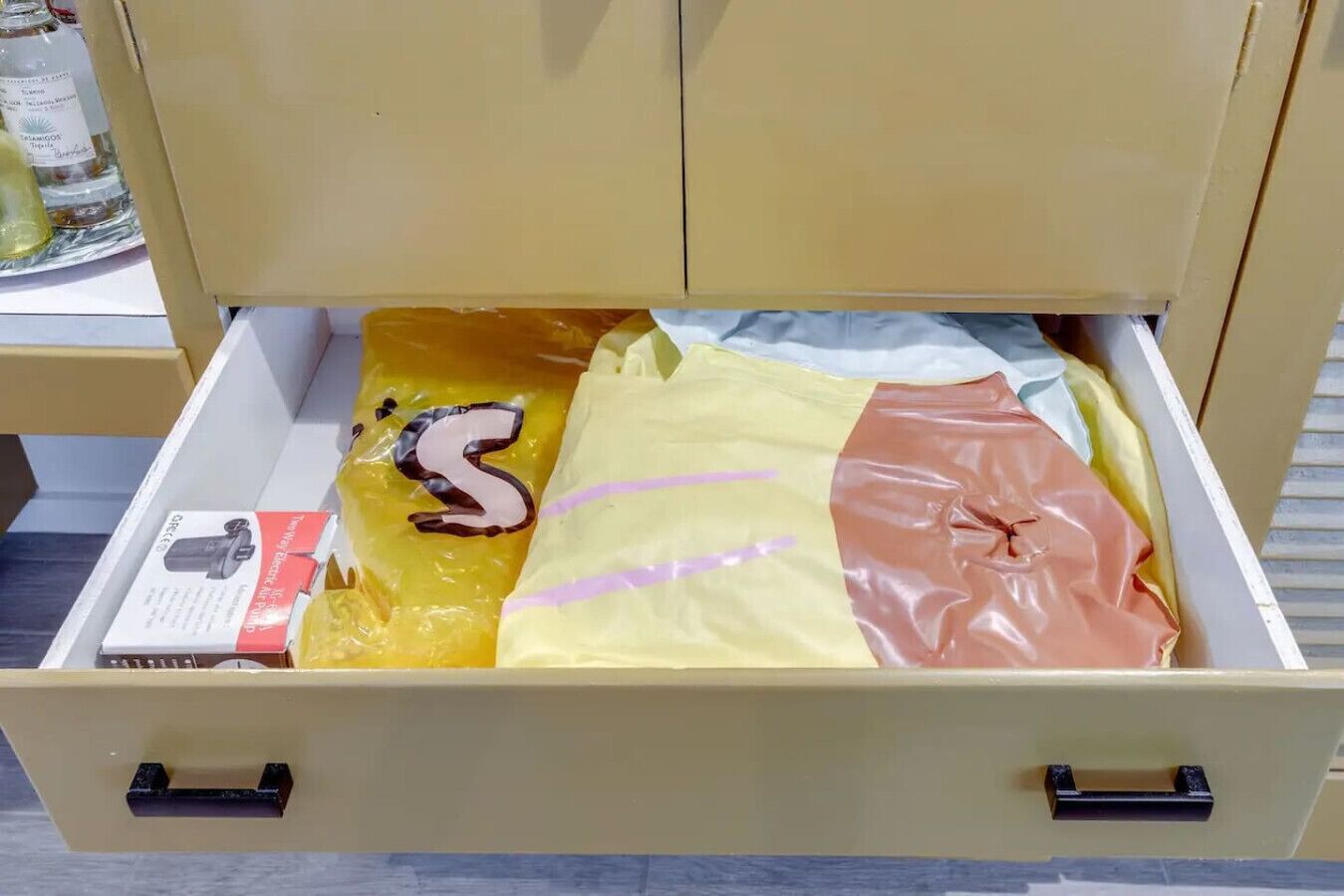 Un cajón con una bolsa de plástico amarilla, una caja roja y blanca, y una bolsa de papel marrón.