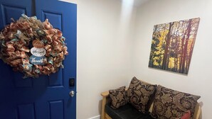 A blue door with a 'Blessed Thanks' wreath, a wooden bench, and a patterned wall hanging. - Cozy 1-bedroom studio in charming Grants perfect for your getaway (Grants)