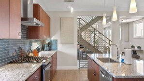 Cocina moderna con encimeras de granito, electrodomésticos de acero inoxidable y una isla central.