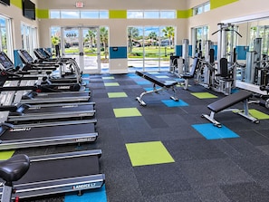 Une salle de sport équipée de tapis de course, d’un banc et d’appareils de musculation.
