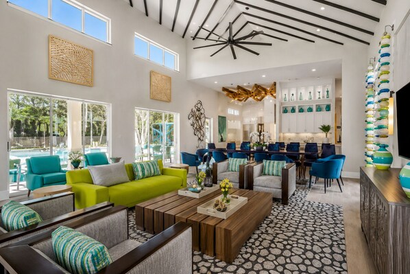 Un vaste espace de vie avec vue sur la piscine, un mobilier moderne et une cuisine à l’arrière-plan.