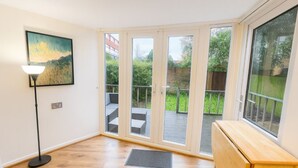 Una stanza con un'ampia porta-vetrina che dà su una zona esterna con un patio in legno e un giardino.
