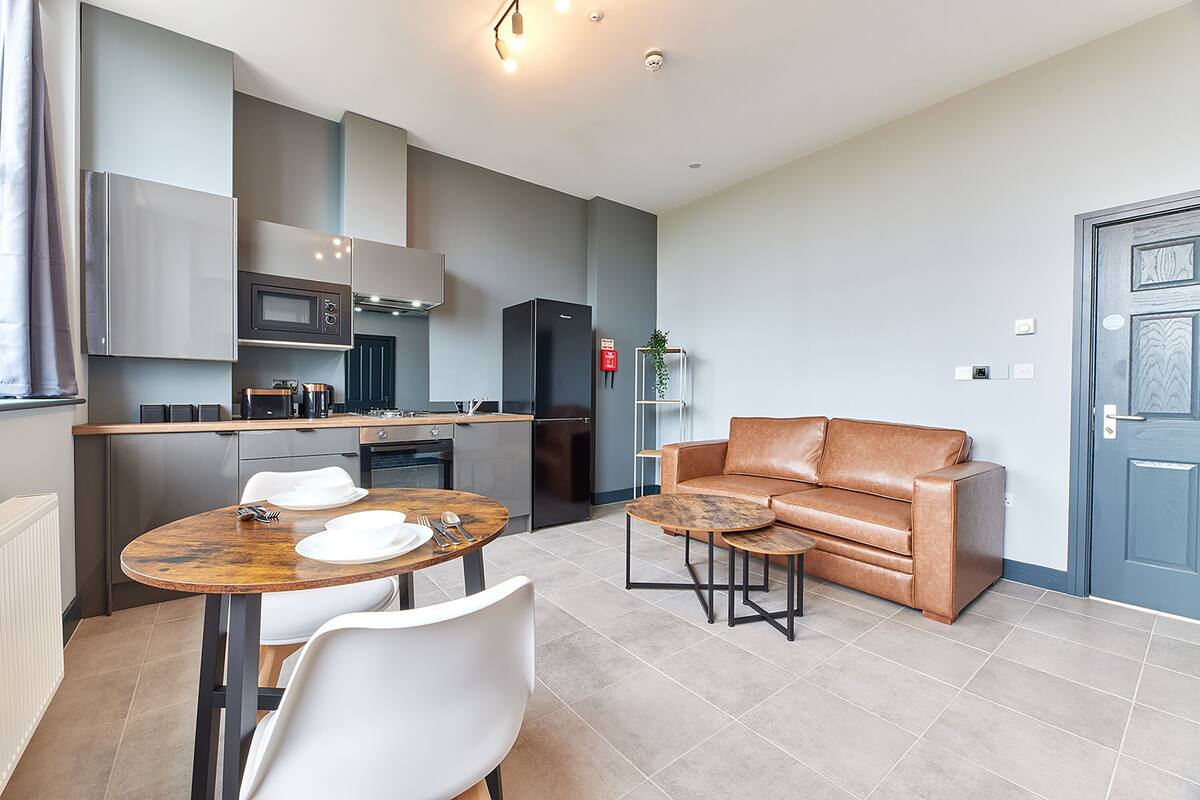 A modern kitchen with a dining area, including a table with chairs, a sofa, and a small coffee table.