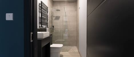A modern bathroom with a shower, toilet, and sink.