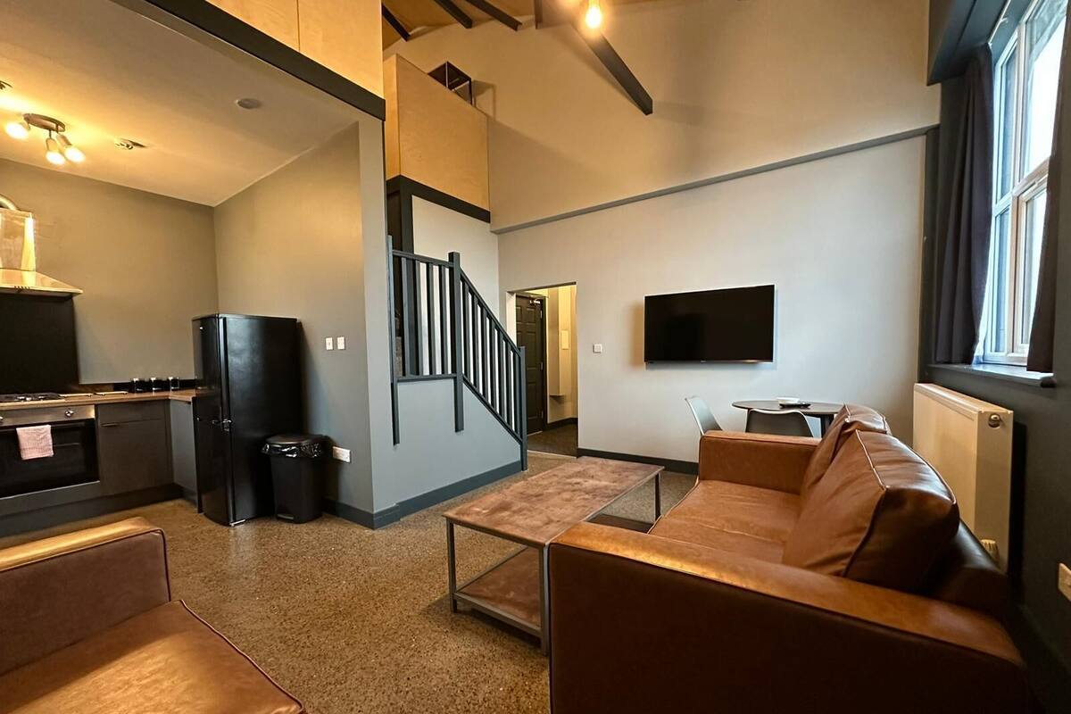 A modern living room with a sofa, a coffee table, and a TV mounted on the wall.