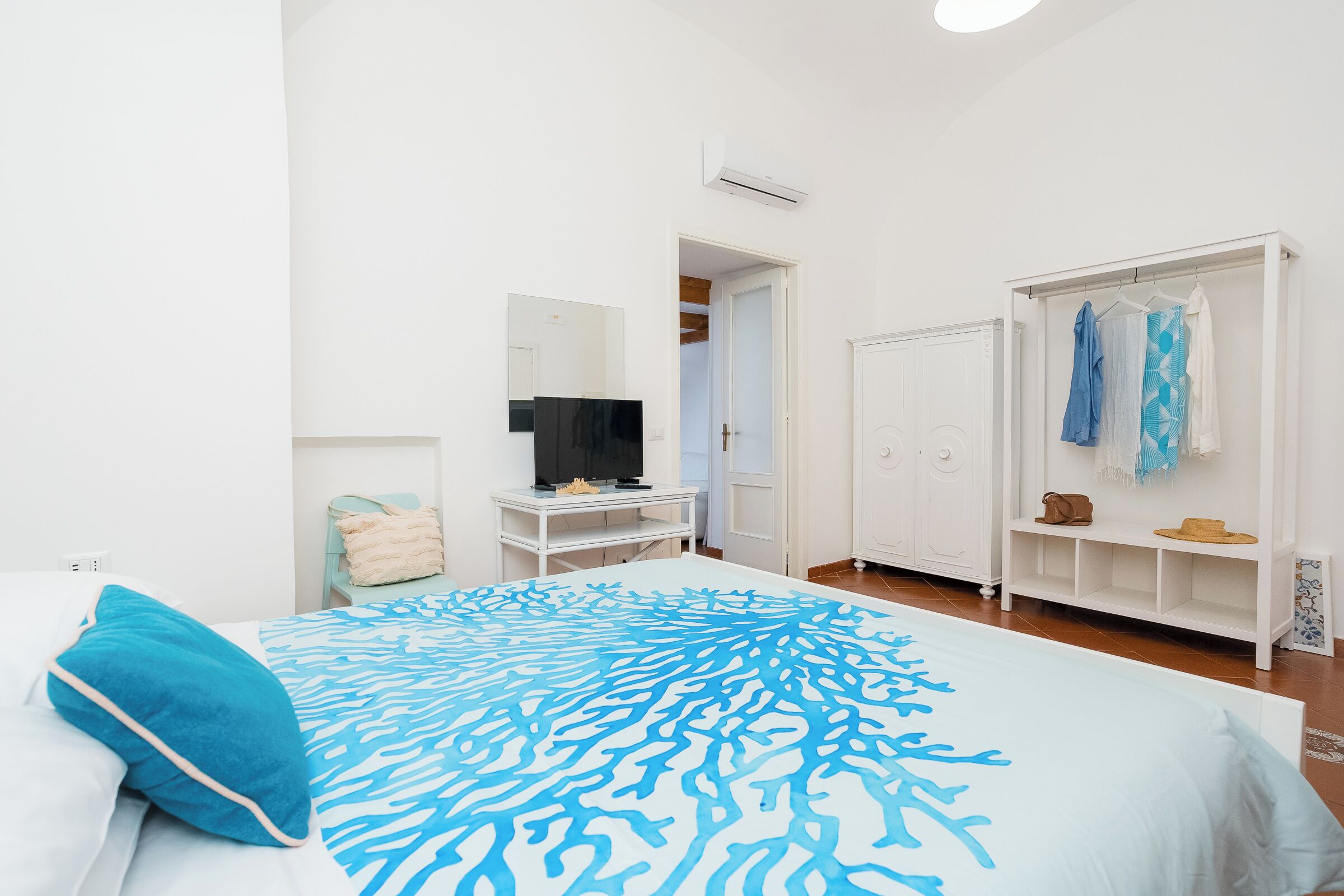 Una camera da letto con un letto, una televisione, un armadio e uno specchio.