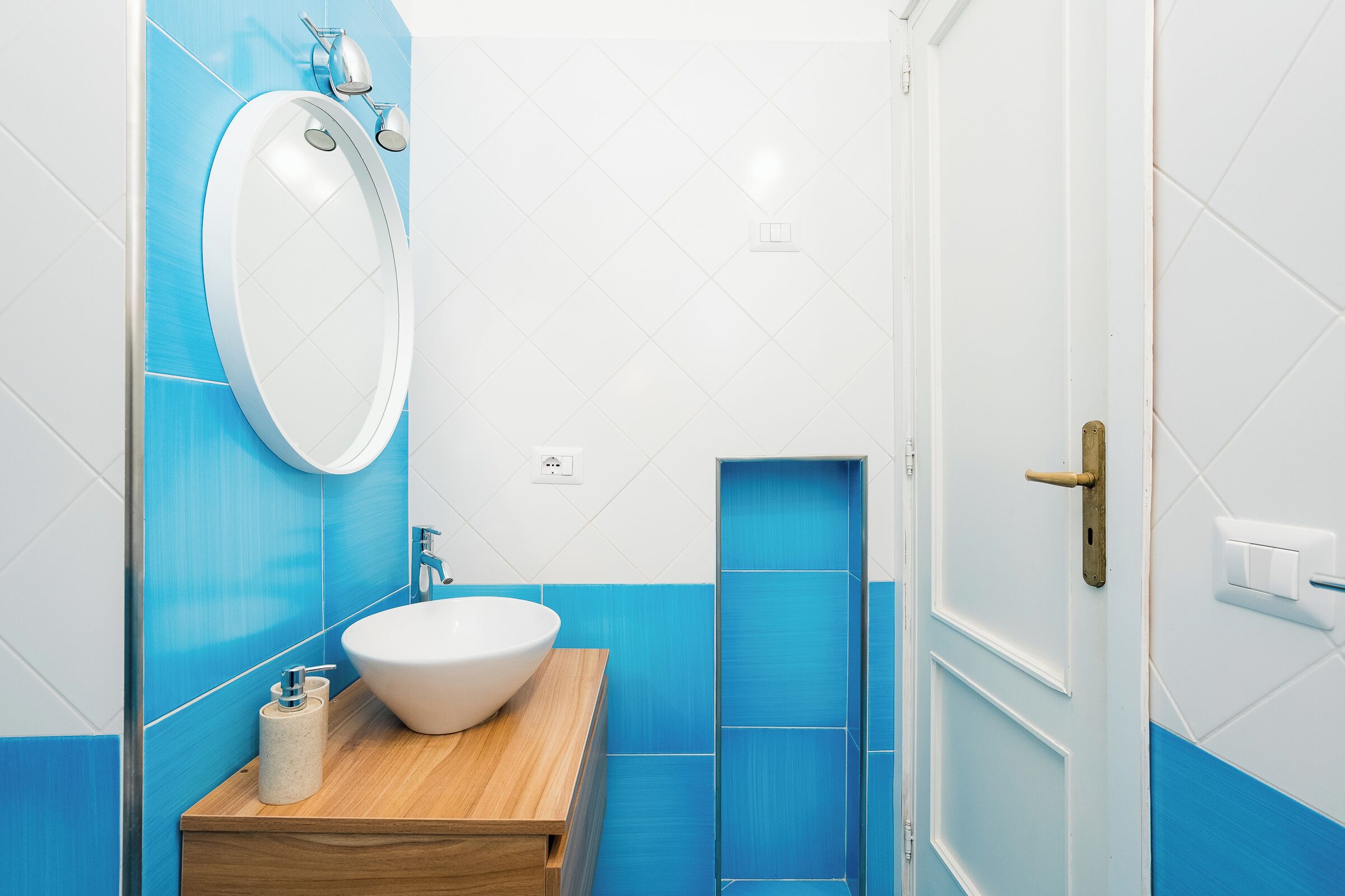 A bathroom with a wooden vanity, a white sink, and a mirror.
