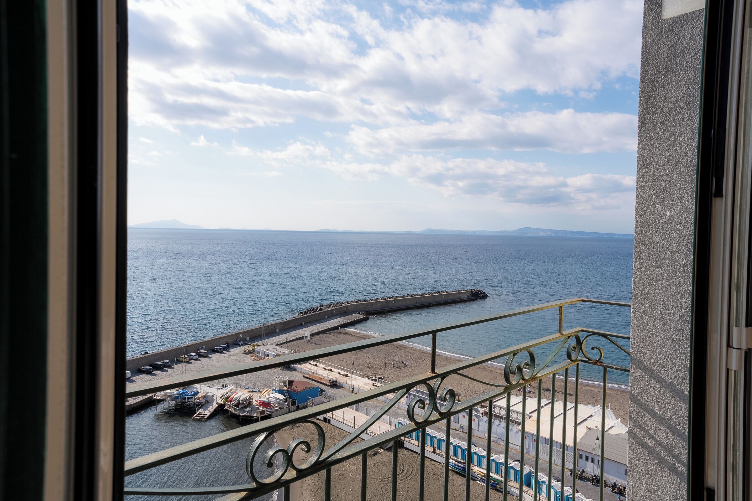 A balcony with a view of a beach and the sea.