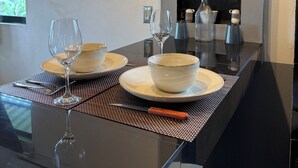 Et moderne spiseområde med et glasbord, hvide tallerkener og klare vinglas.