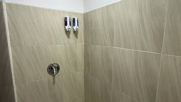 A small, tiled shower room with a wooden ceiling and two hand sanitizer dispensers mounted on the wall.