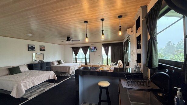 Et moderne hotelværelse med træloft, to senge, et spiseområde og udsigt til det fri.