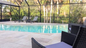 Zona de piscina con sillones de playa y mobiliario de mimbre.