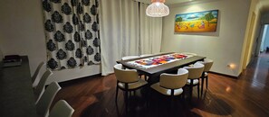 A dining area with a wooden table, six chairs, a patterned curtain, a hanging light fixture, and a painting on the wall. - Experience vibrant city living, steps away from all that Quito has to offer (Quito)