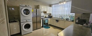A compact kitchen with a washing machine, oven, and microwave. - Experience vibrant city living, steps away from all that Quito has to offer (Quito)