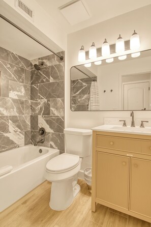 A modern bathroom with a bathtub, toilet, and vanity. - Charming Townhouse in Tucson. (Tucson)