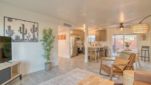 A spacious living room with a large plant, a wooden coffee table, and a TV. - Charming Townhouse in Tucson. (Tucson)