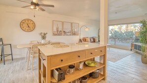 A modern kitchen with a wooden island, a ceiling fan, a large wall clock, and artwork. - Charming Townhouse in Tucson. (Tucson)