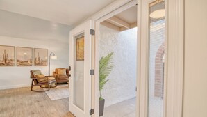 A well-lit hallway with a wooden floor, a door leading to another room, and a potted plant. There are framed pictures on the wall and a lamp in the corner. - Charming Townhouse in Tucson. (Tucson)