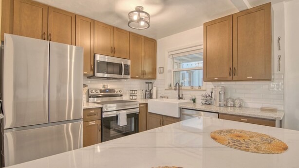 A modern kitchen with wooden cabinets, stainless steel appliances, a marble countertop, and a central island. - Charming Townhouse in Tucson. (Tucson)