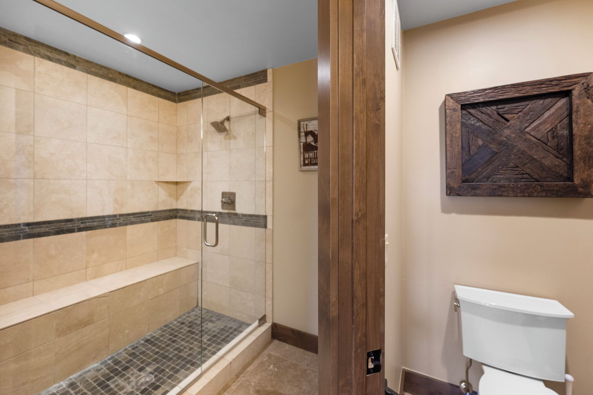 Une salle de bain avec une douche à parois de verre, des toilettes et un mur d’accent en bois.