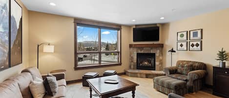 A living room with a fireplace, a sofa, a coffee table, and a television mounted on the wall.