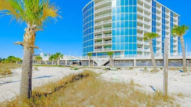 A modern hotel with a curved facade, multiple balconies, and a beachside location. - Panoramic Gulf Views- Two bedroom condo-On the Beach with Balcony! (Biloxi)