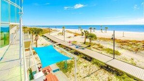 A beachside view with a clear sky, a sandy beach, and a few palm trees. - Panoramic Gulf Views- Two bedroom condo-On the Beach with Balcony! (Biloxi)