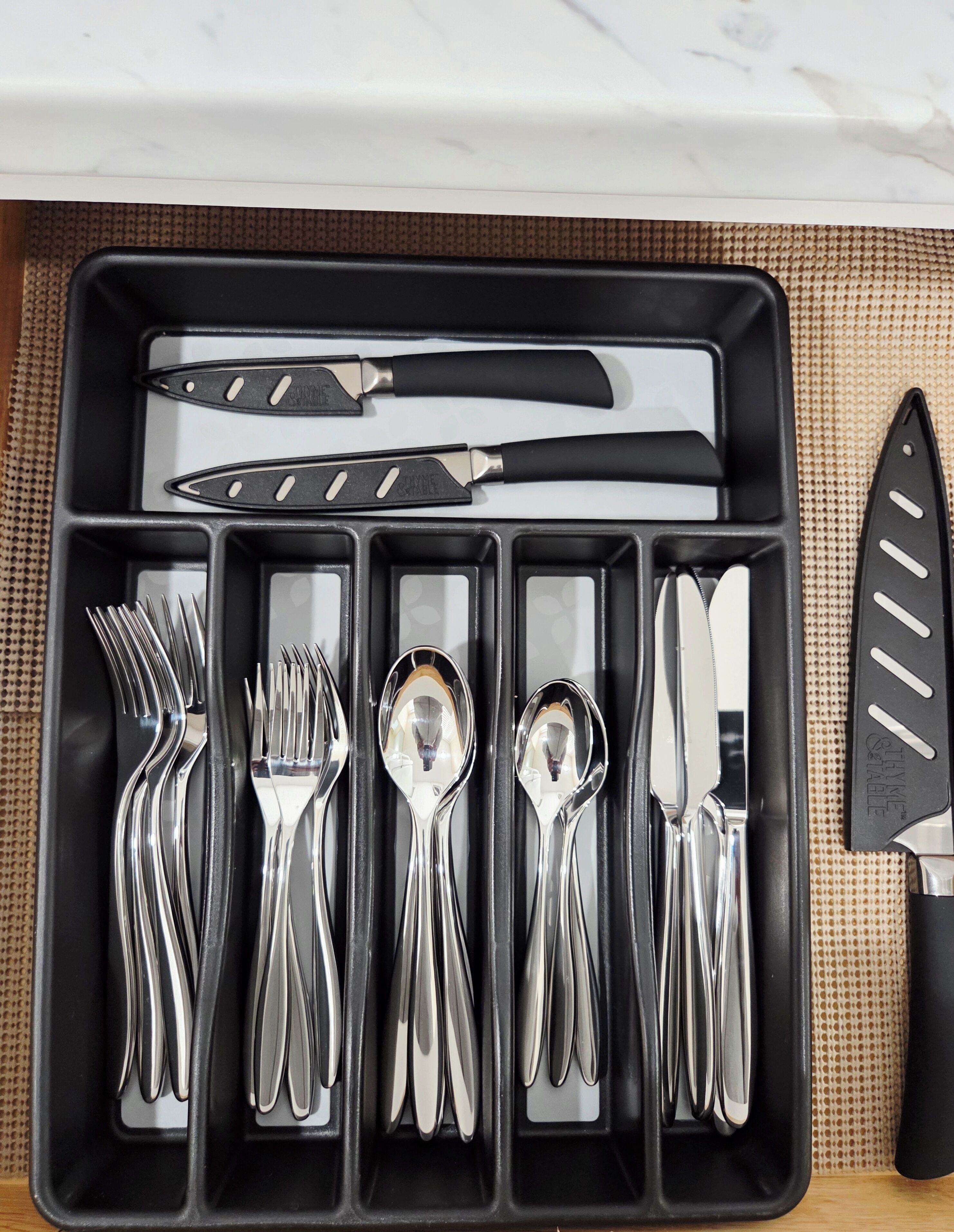 A black tray with cutlery including forks, spoons, and knives.