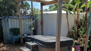 Eine Holzterrasse mit Whirlpool, einer Pergola und Blumentöpfen.
