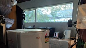 Eine kleine Küche mit Kühlschrank, Mikrowelle, Kaffeemaschine und einem Tisch.