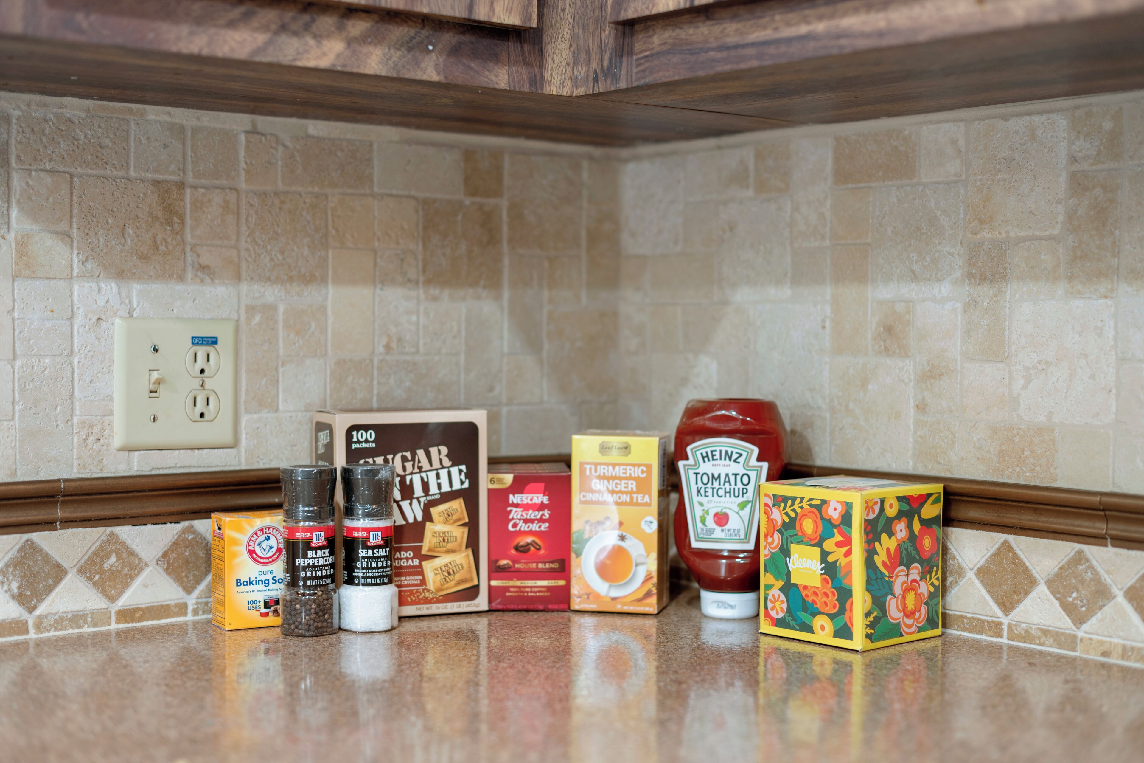 Una encimera de cocina con diversos productos alimenticios y una caja de Heinz Tomato Ketchup.