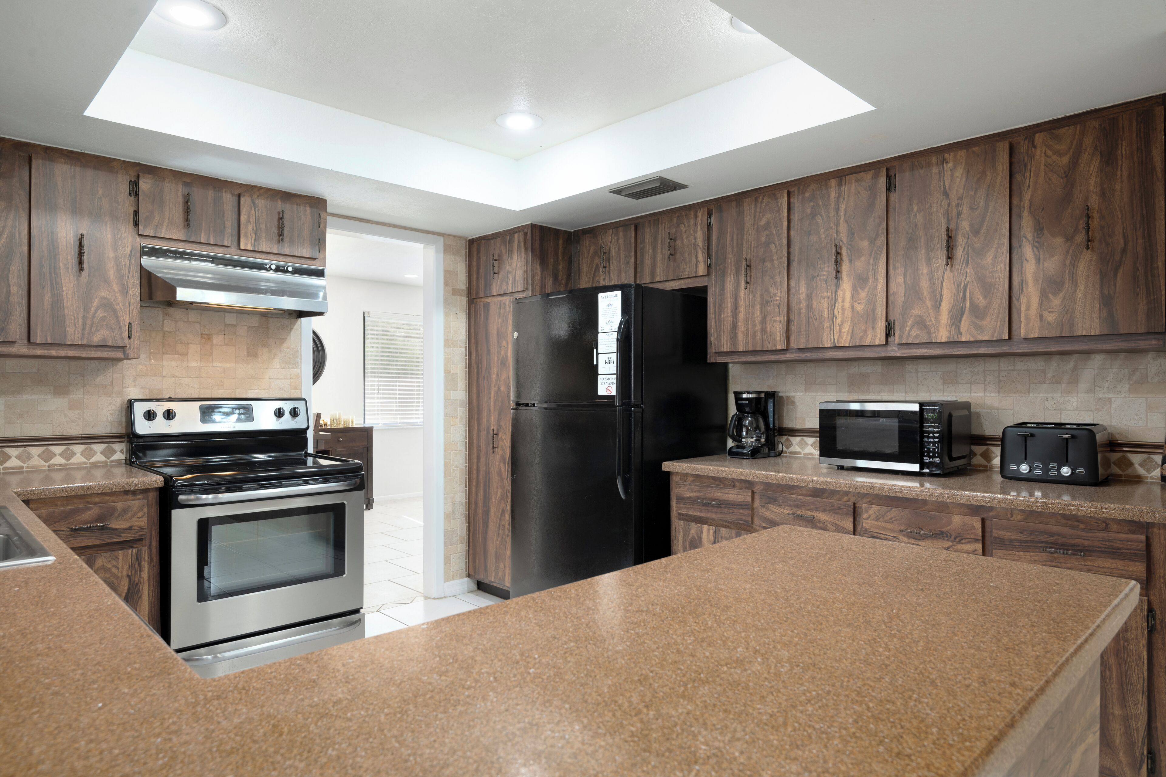 A kitchen with wooden cabinets, a stainless steel oven, a black refrigerator, a microwave, and a toaster.