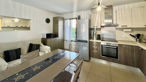 Une cuisine compacte comprenant une table à manger, un réfrigérateur, un four à micro-ondes et une cuisinière.