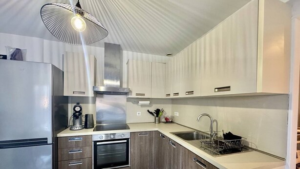 Une cuisine moderne dotée d’appareils électroménagers en acier inoxydable, de meubles en bois et d’un four encastré.