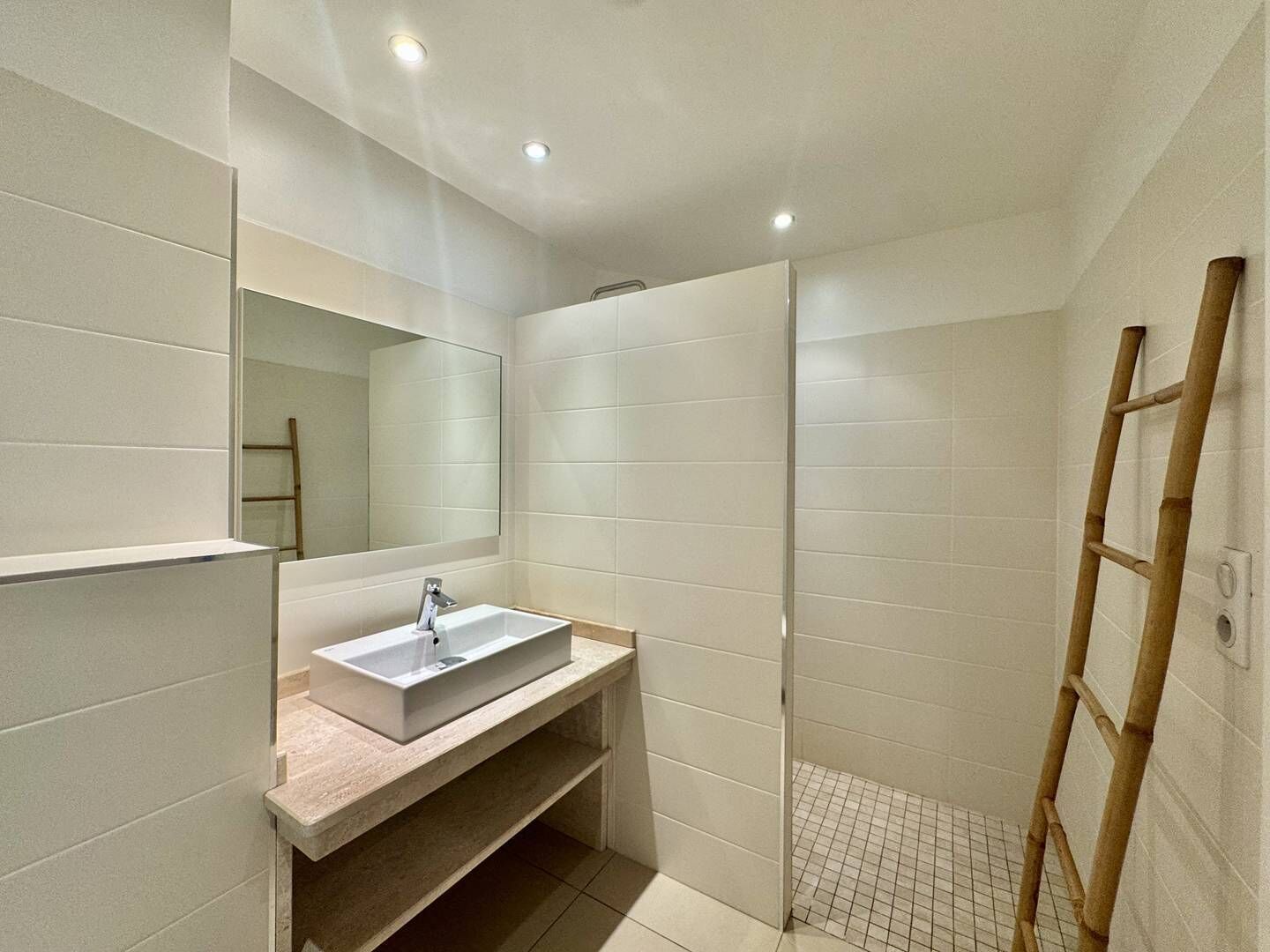 Een moderne badkamer met een rechthoekig wastafel, een spiegel en een douchegedeelte.